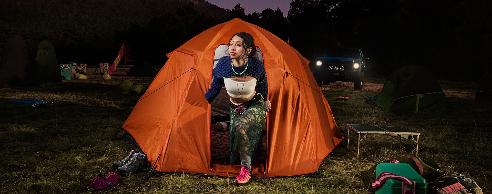 A person emerging from an orange tent dressed in Merrell gear